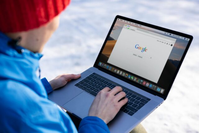 Persoană care citește atent informații despre sănătate pe ecranul unui laptop, acasă, la masa din bucătărie